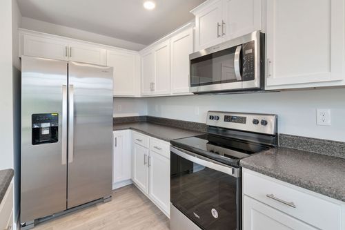 Bright modern kitchen with stainless steel appliances, white cabinets, and gray countertops