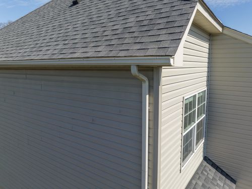 Gray house roof and siding with white trim and a rain gutter, viewed from above