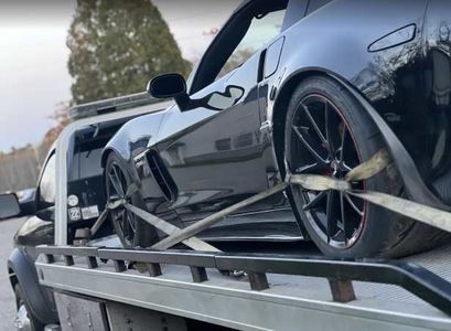 A black sports car is being towed by a tow truck.