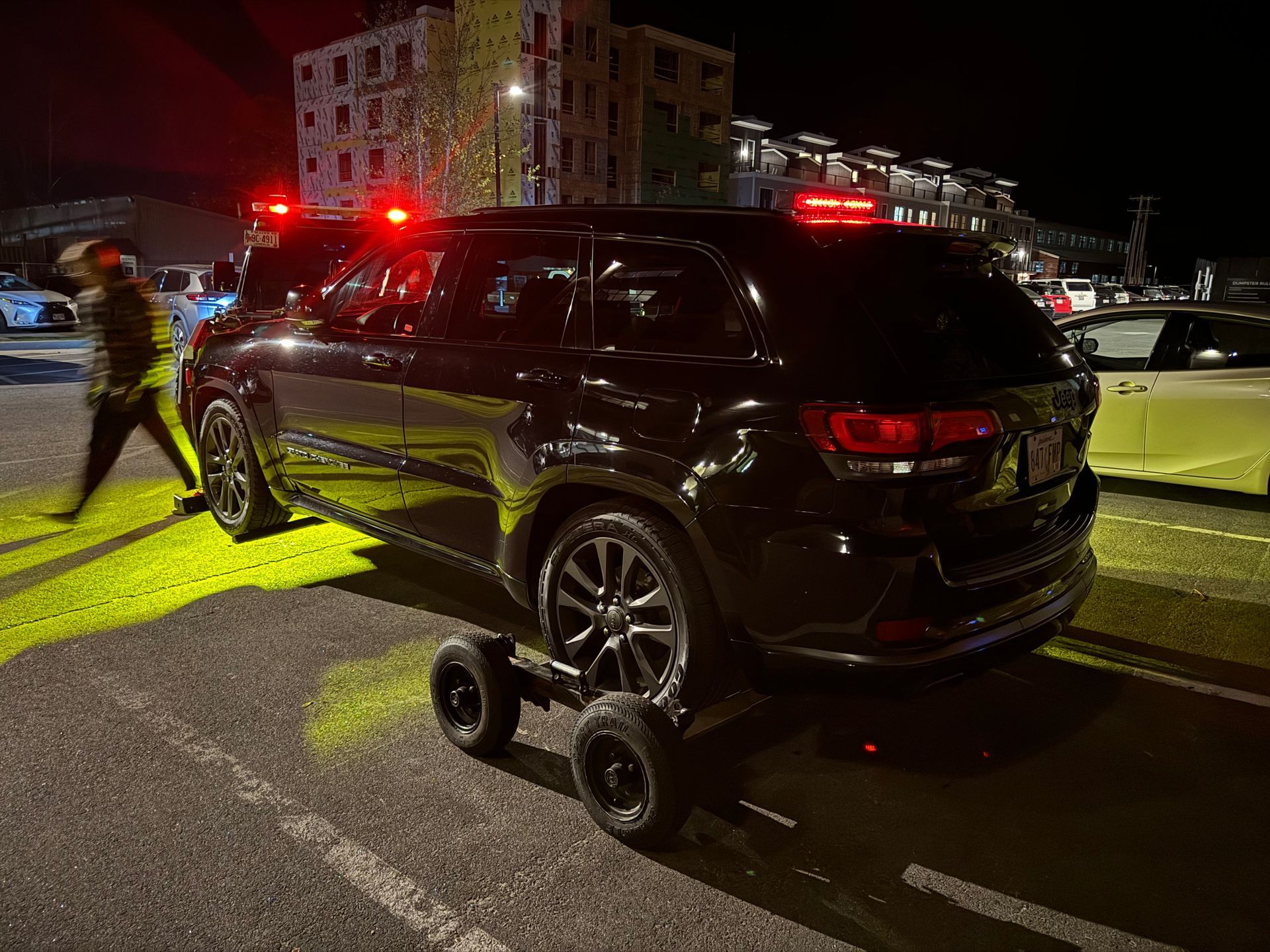 A black suv with wheels attached to it is parked on the side of the road.