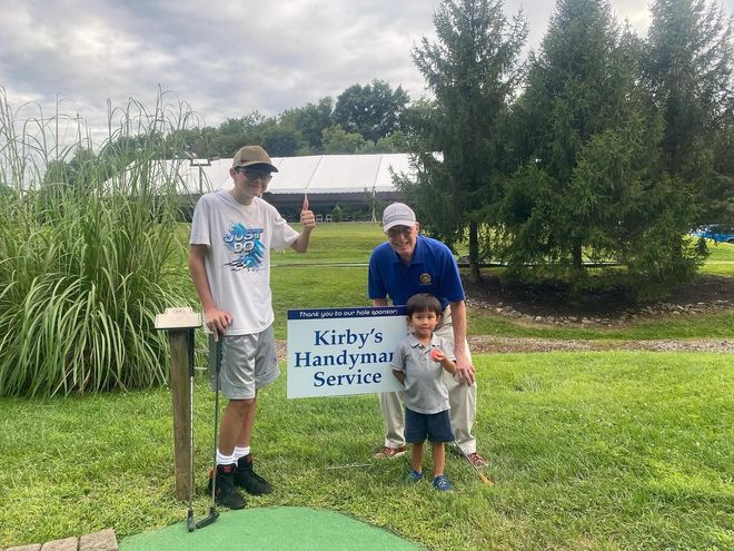 Two people and a child holding a sign for 