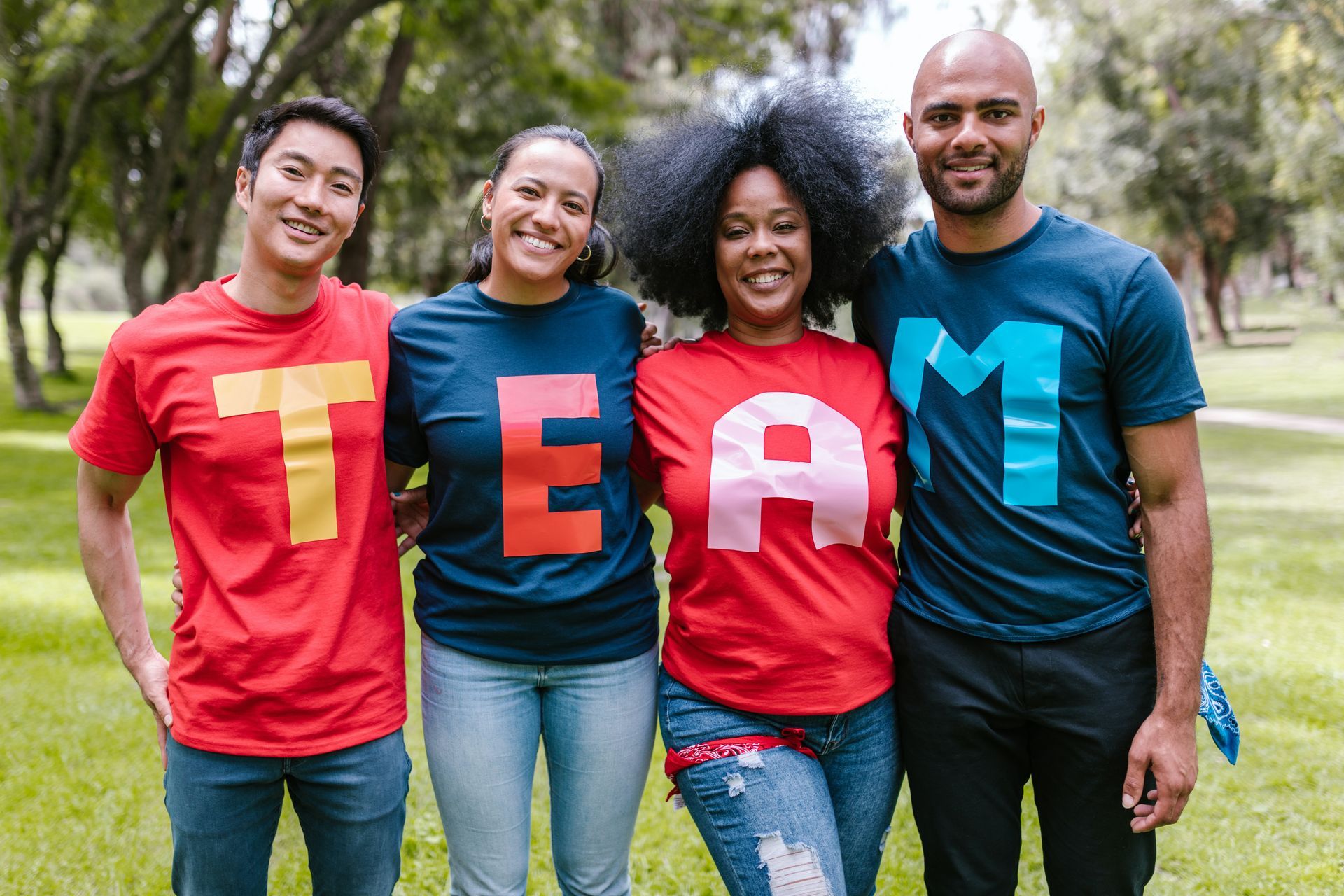 Vier mensen staan ​​in een park, gekleed in shirts met daarop 