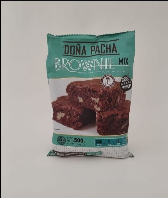 Un paquete de mezcla para brownies Doña Pacha, con una imagen de brownies sobre un fondo liso de color blanco roto.