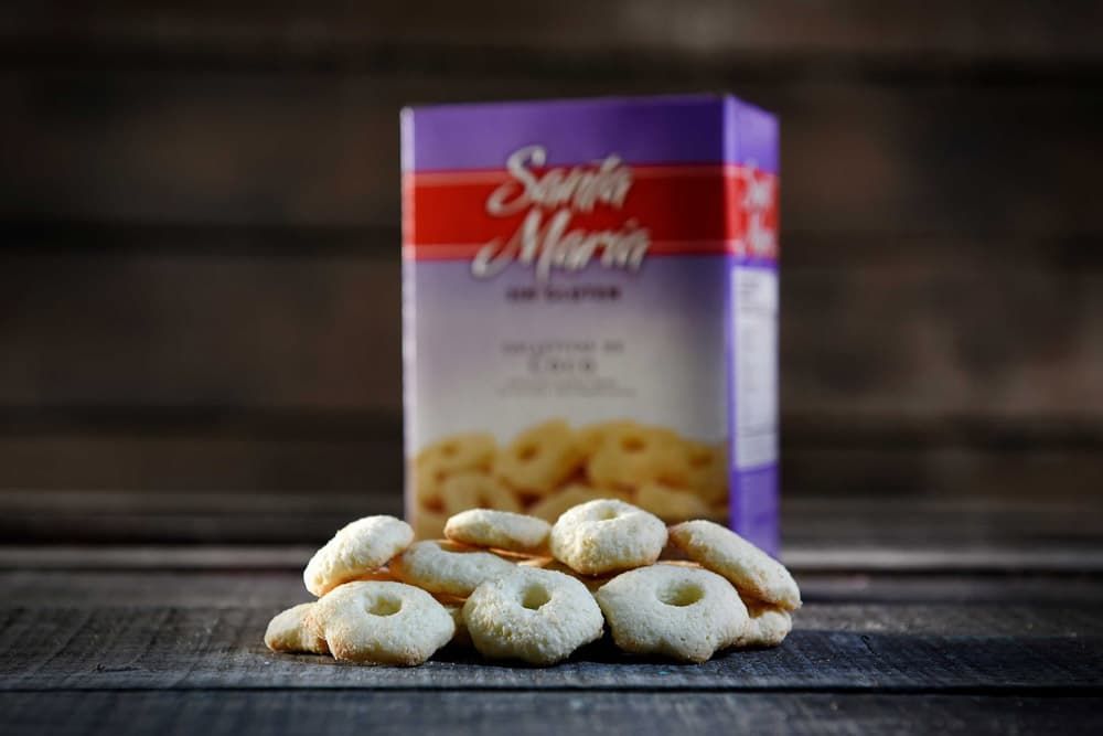 Una pila de galletas sin gluten con forma de anillo reposa frente a una caja borrosa