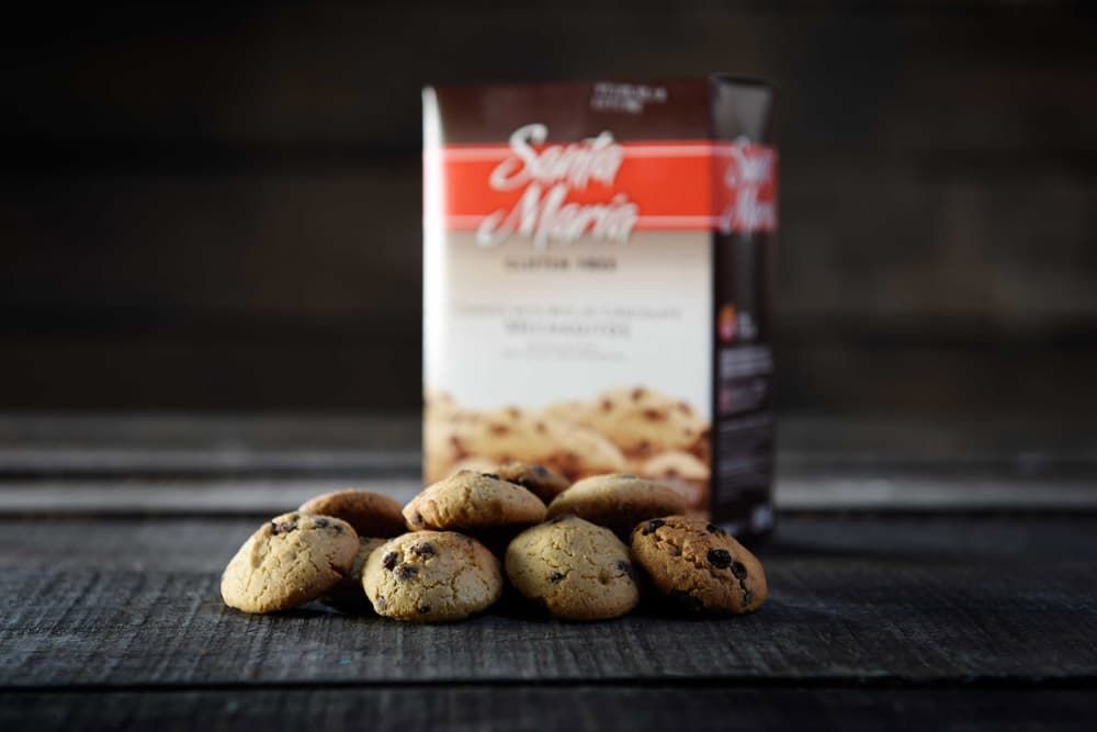 Un pequeño montón de galletas con chispas de chocolate frente a una caja