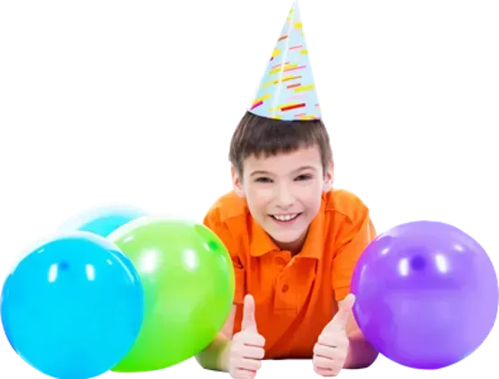 a young boy wearing a party hat is laying on the floor with balloons and giving a thumbs up .