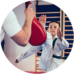 a young boy is practicing karate with a red kick pad .