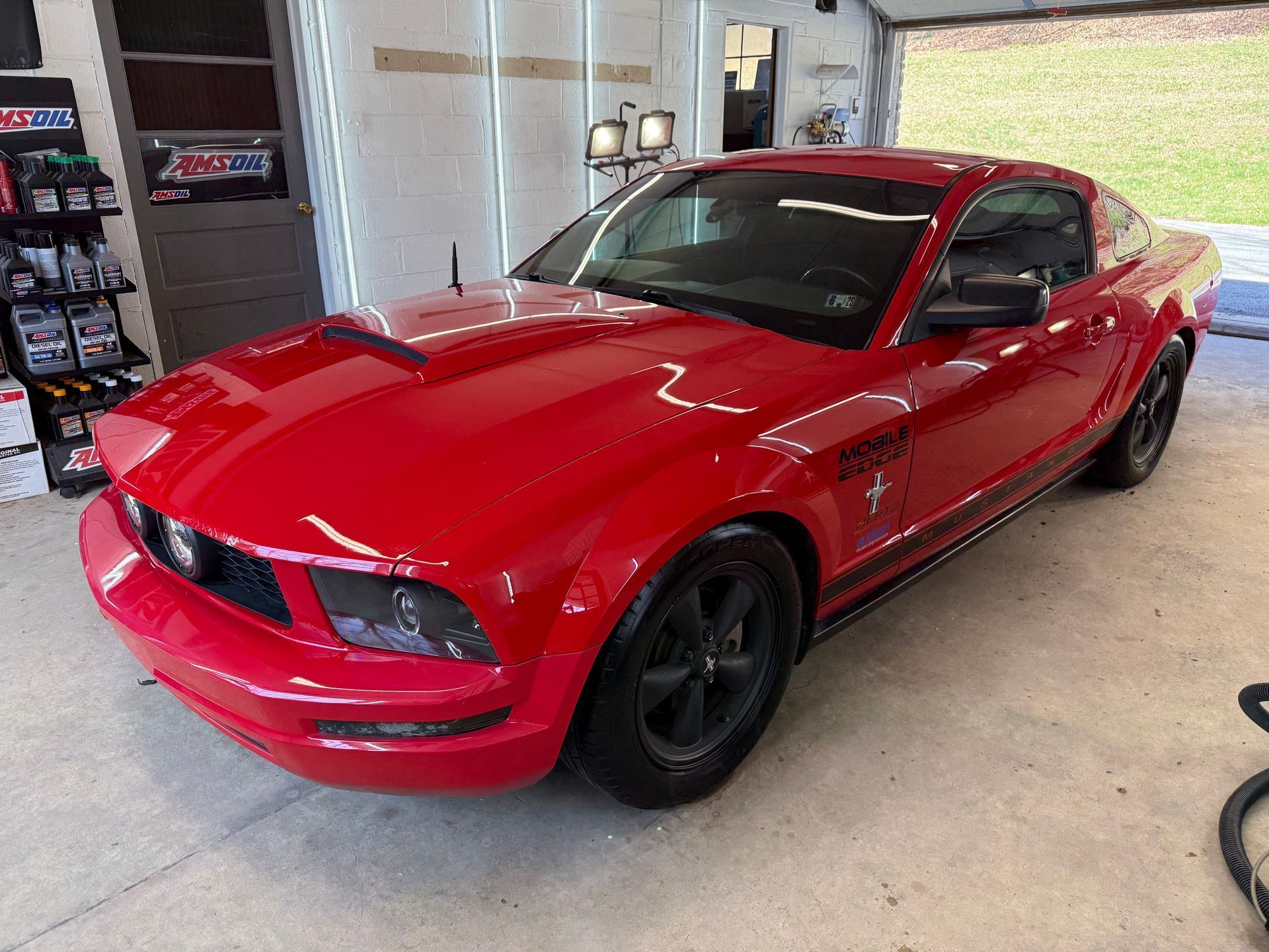 Red sports car parked in a garage, front-left view.