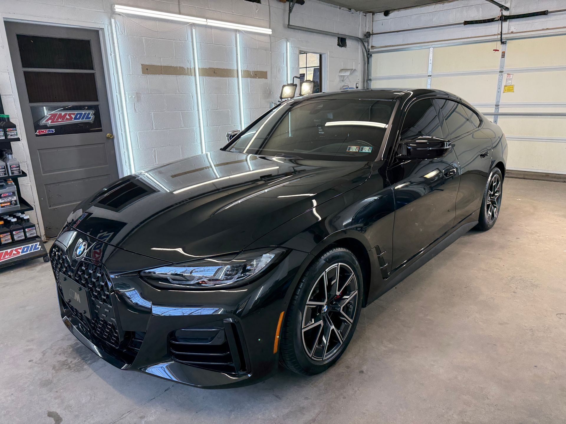 Black BMW sedan parked in a garage with white walls and a concrete floor