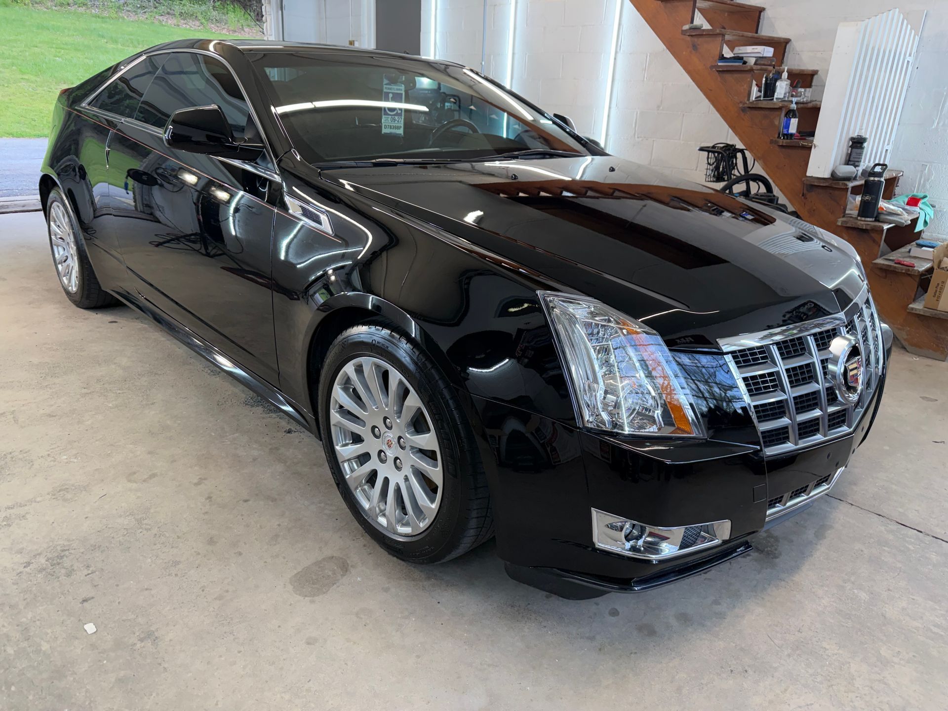 A black audi a5 convertible is parked in a garage next to a staircase.