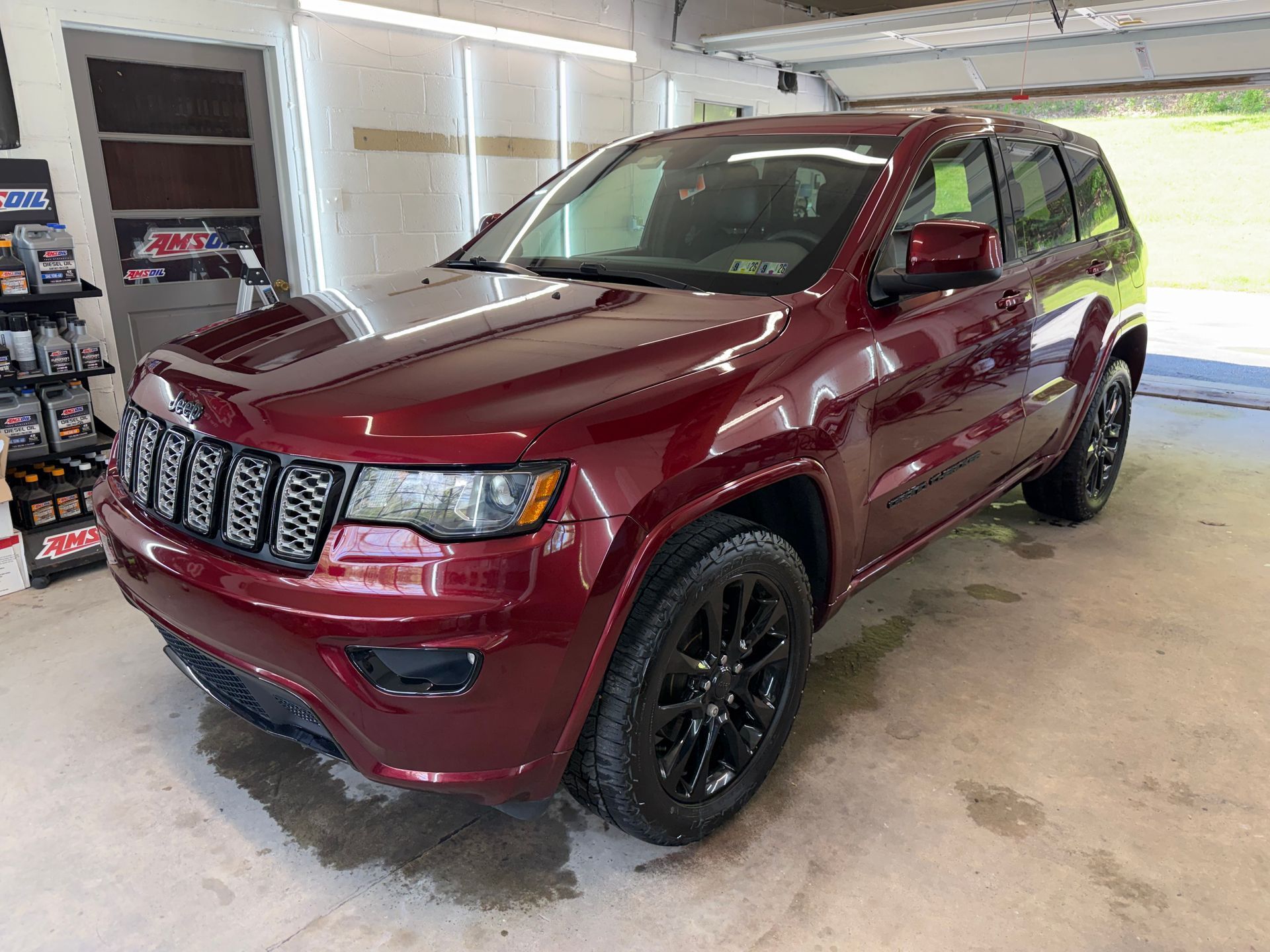 Maroon Jeep SUV parked in a garage, shown from the front-left side.