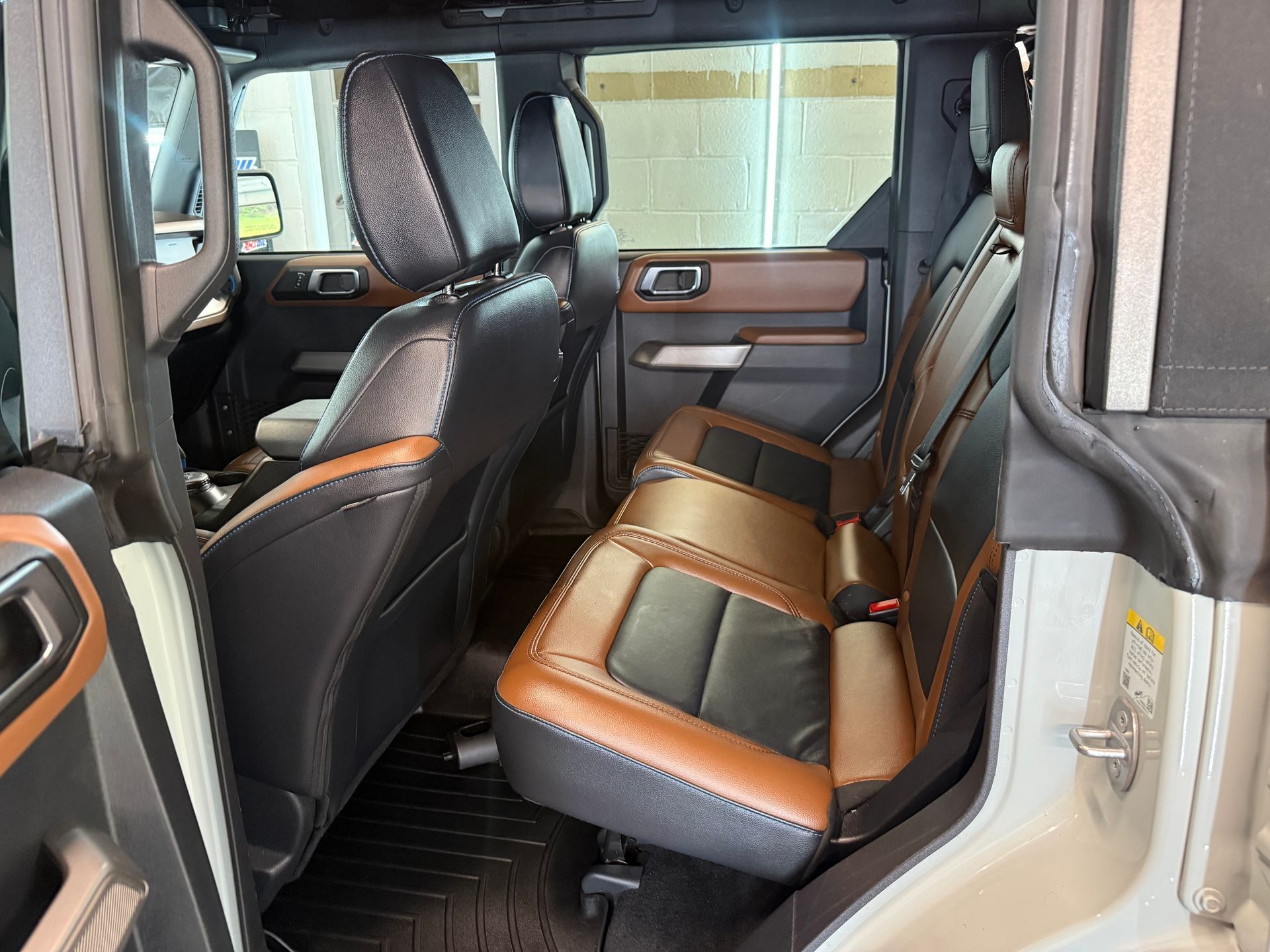 Rear passenger area of a truck with black and tan leather seats and a bench-style rear seat.