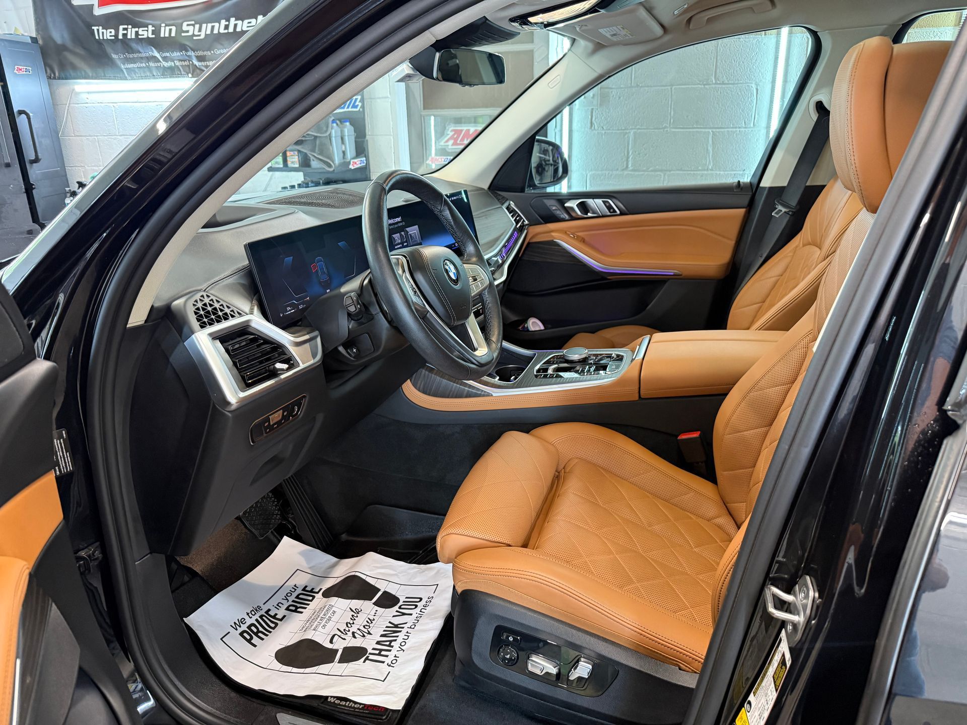 Luxury car interior with tan leather seats and dashboard, driver’s door open