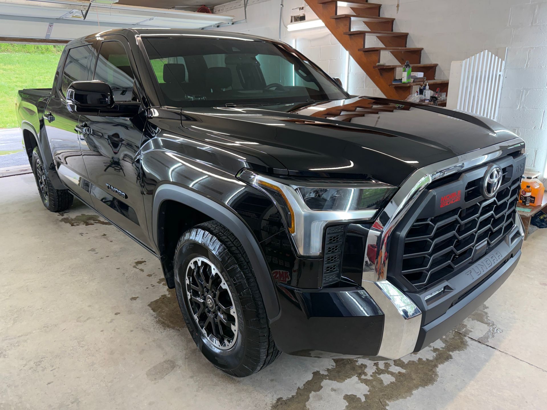 Black GMC pickup truck parked in a garage with the hood open, front-left view