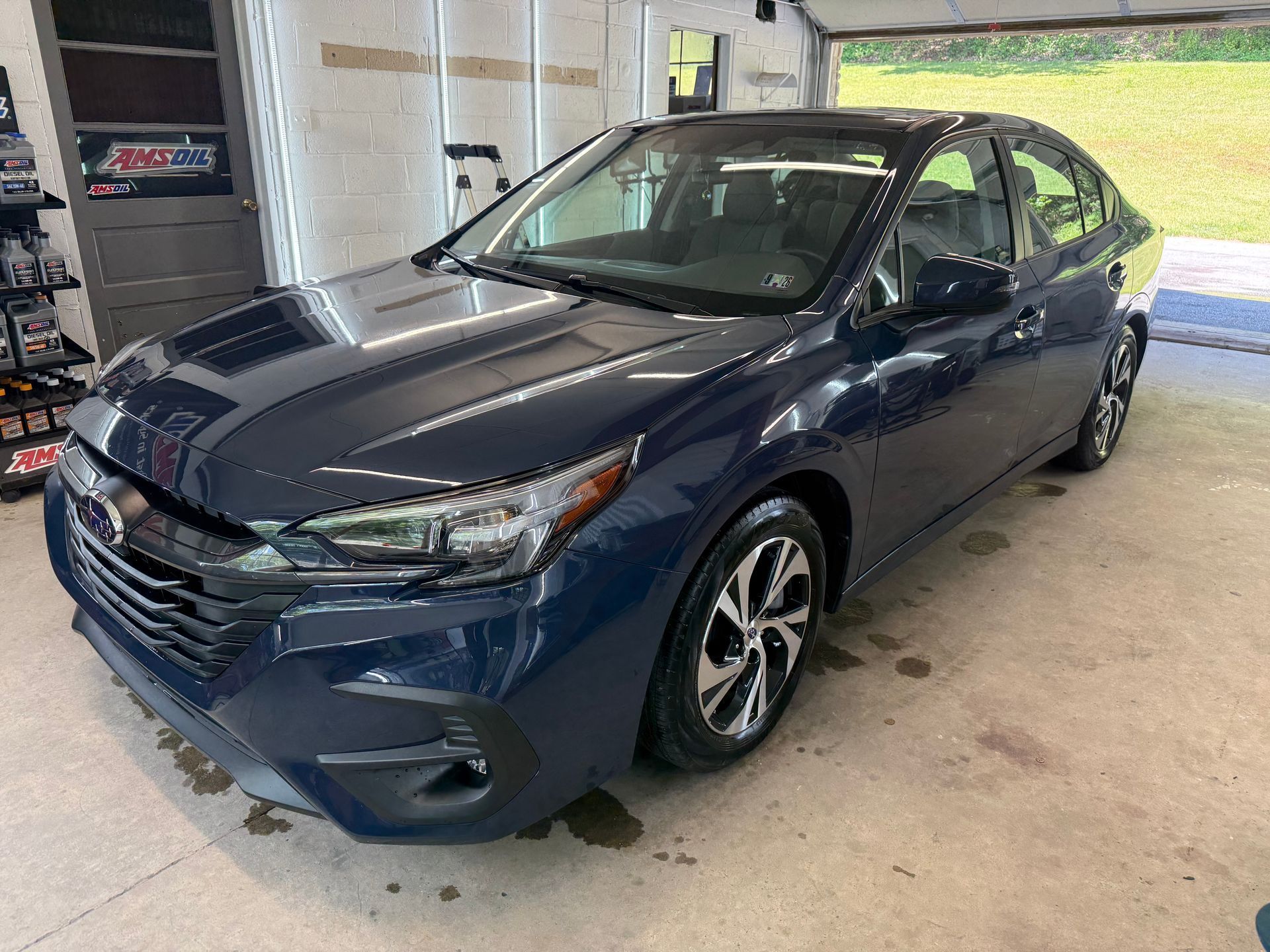 Blue sedan parked inside a garage with overhead lights on