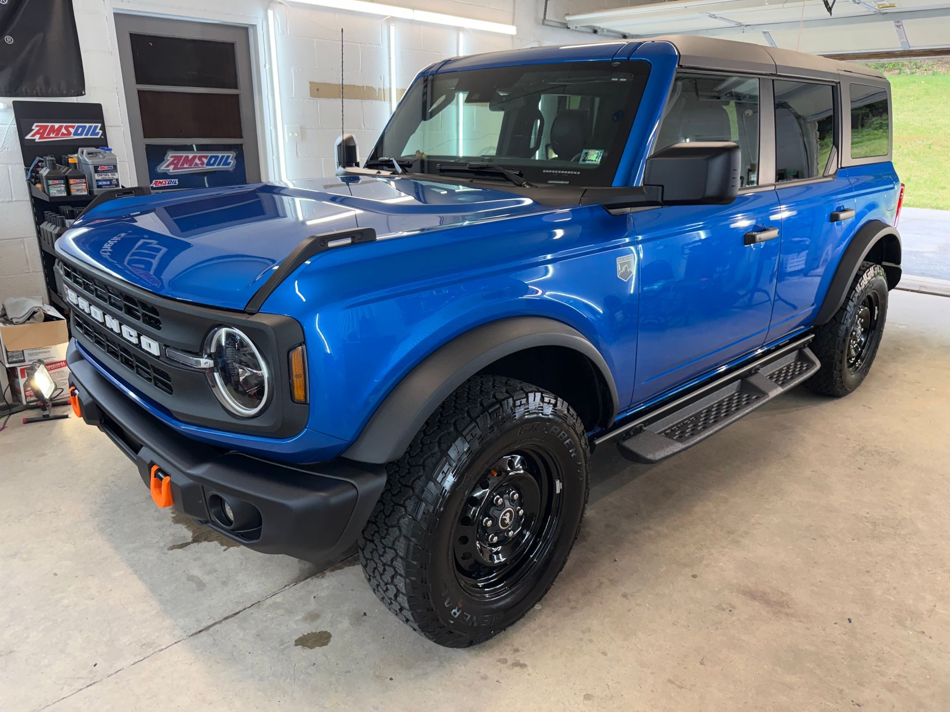 Blue off-road SUV with black wheels parked indoors in a garage or showroom.