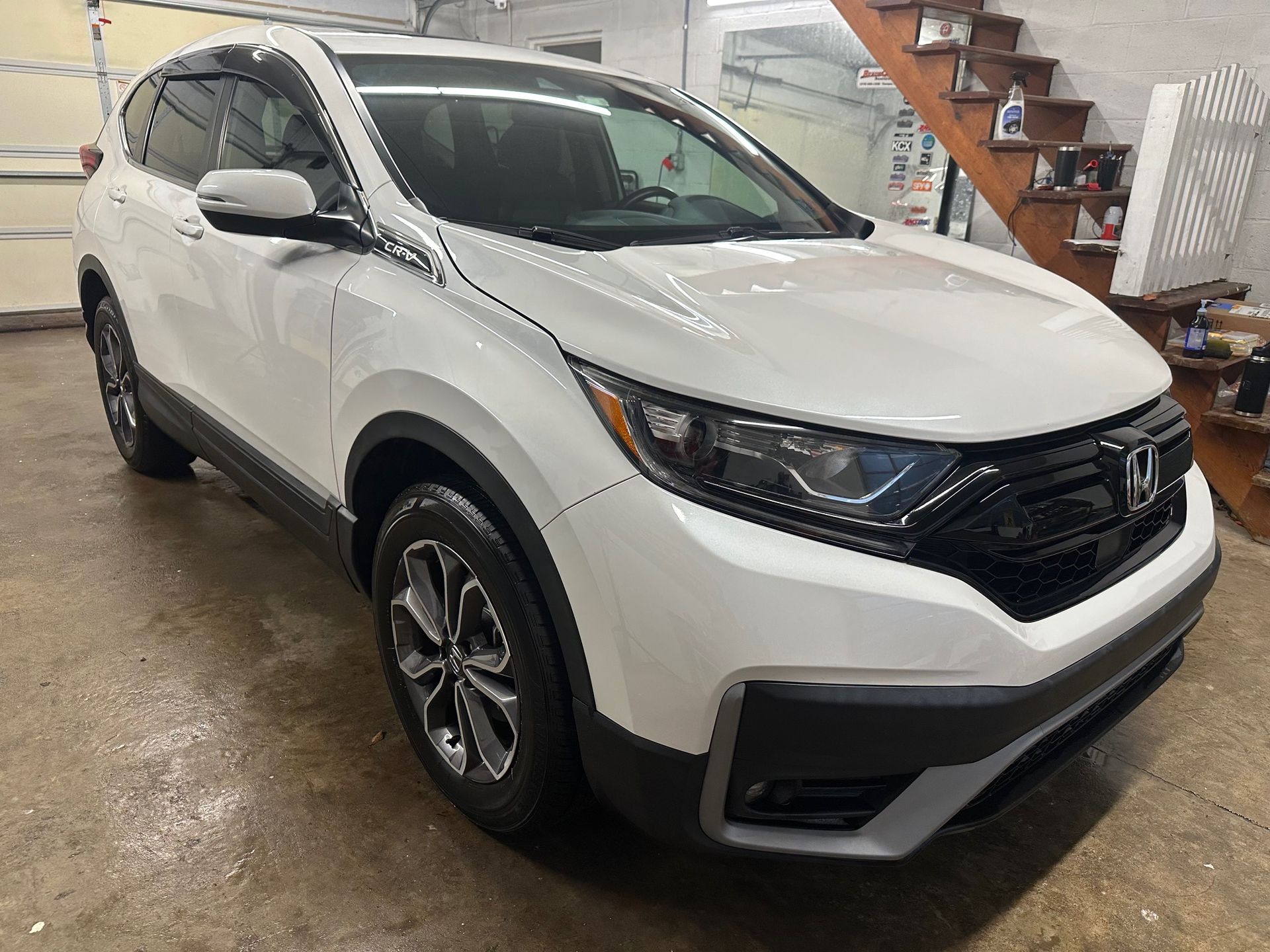 White Honda CR-V SUV parked indoors; black trim, front view.