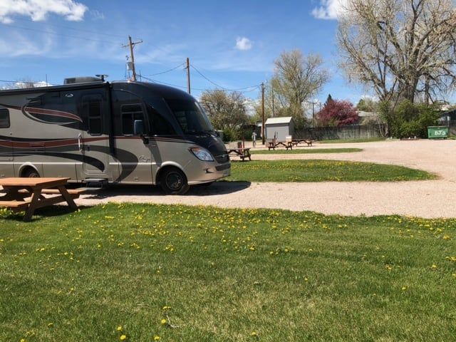 A rv is parked in a grassy area next to a picnic table.