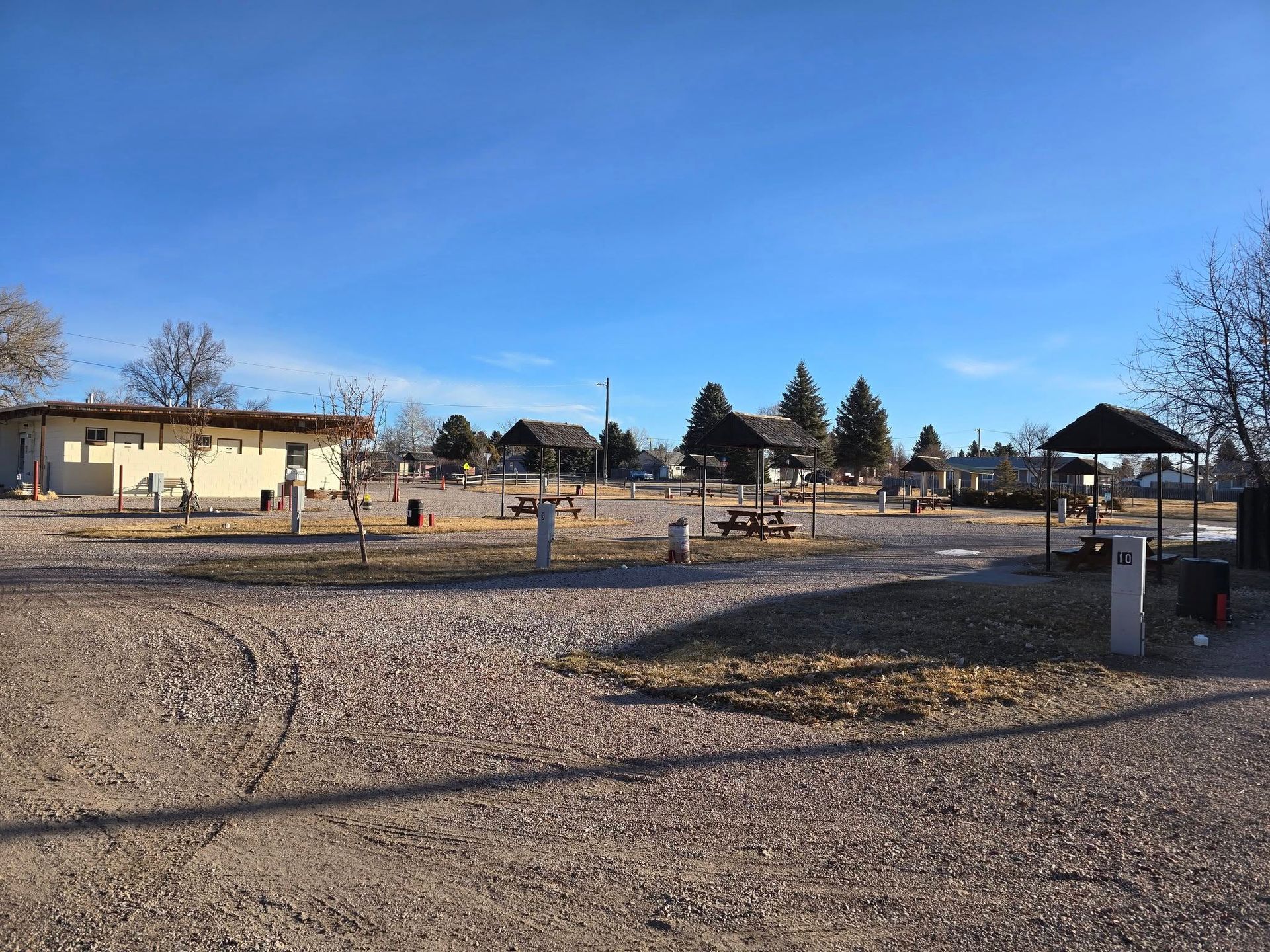 A gravel area with a house in the background and a picnic area in the foreground.