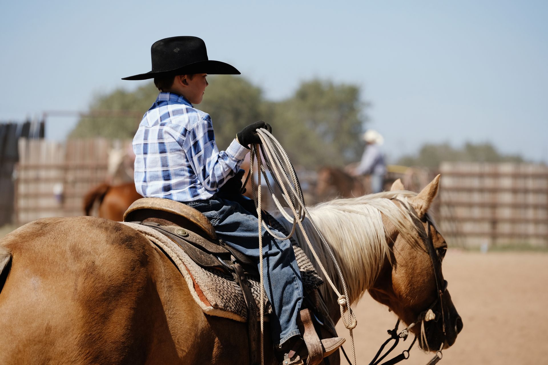 A young boy in a cowboy hat is riding a horse.