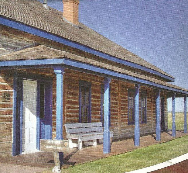 A log cabin with a blue porch and a bench