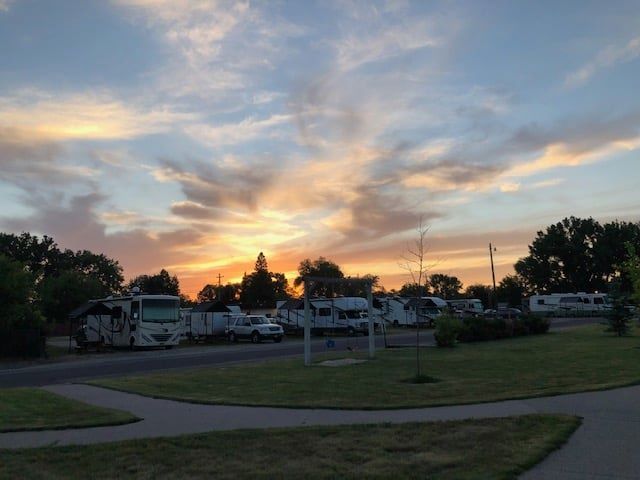 A group of rvs are parked in a parking lot at sunset.
