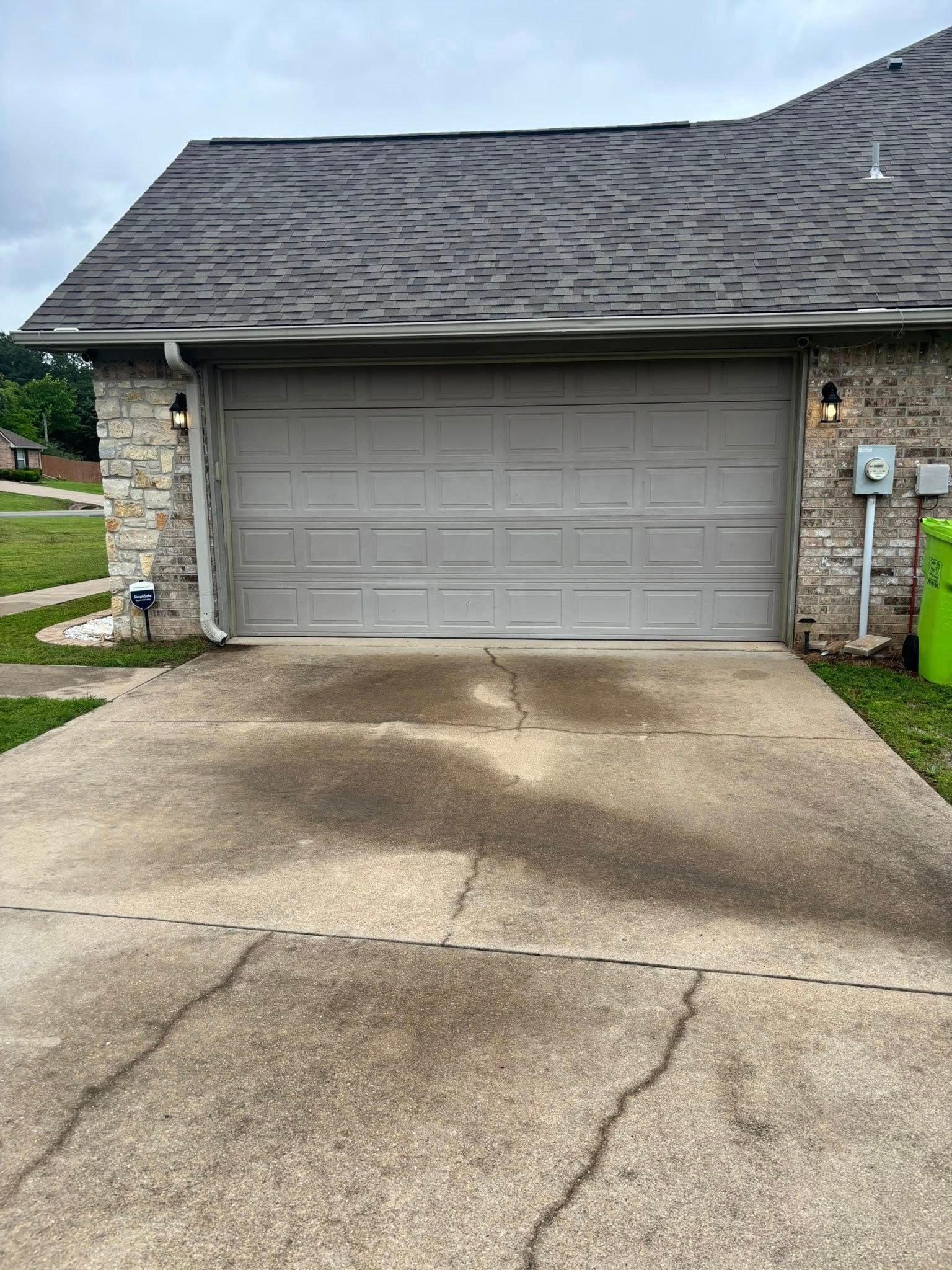 Suburban house with gray garage door and wet concrete driveway after rain