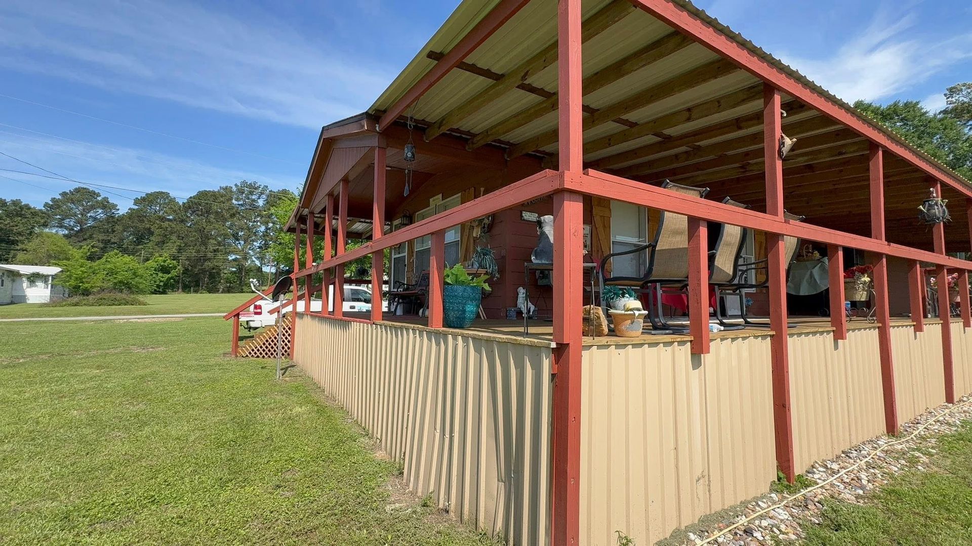 Open-sided red pavilion with beige lower walls on a grassy field