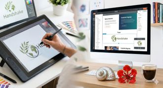 Une main utilise un stylet sur une tablette graphique pour dessiner un logo, tandis qu'un écran d'ordinateur 