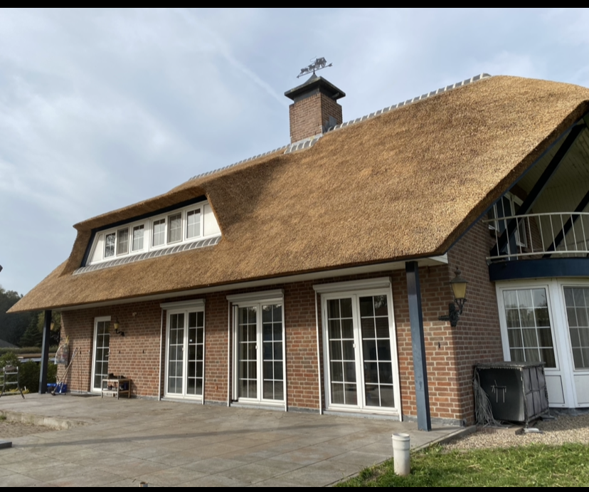 Een groot bakstenen huis met een rieten dak