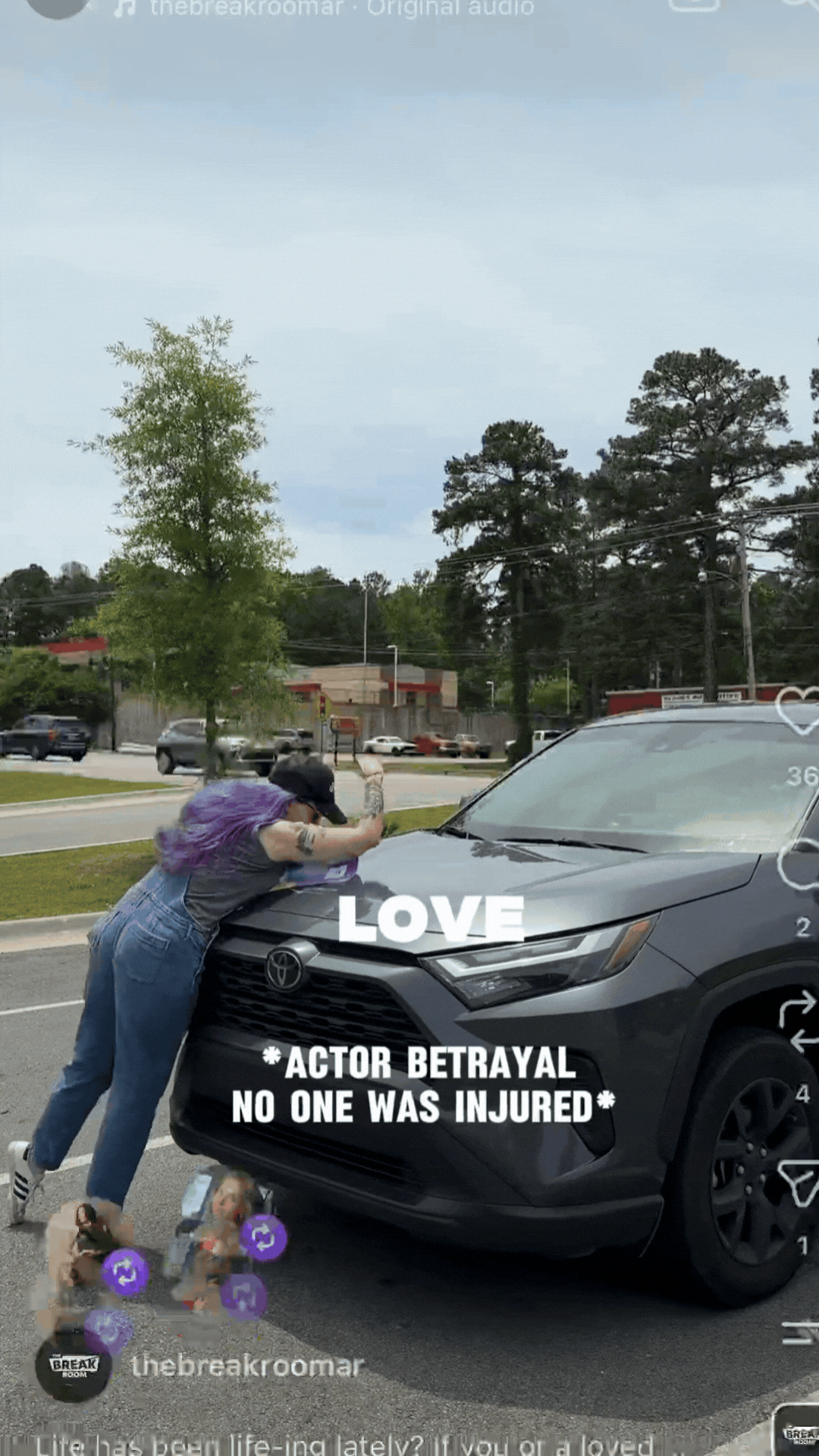 Person leaning on black car with “LOVE” and “NO ONE WAS INJURED” text, in a parking lot