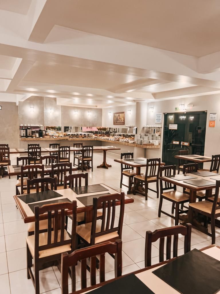 Um restaurante cheio de mesas e cadeiras e um bufê.