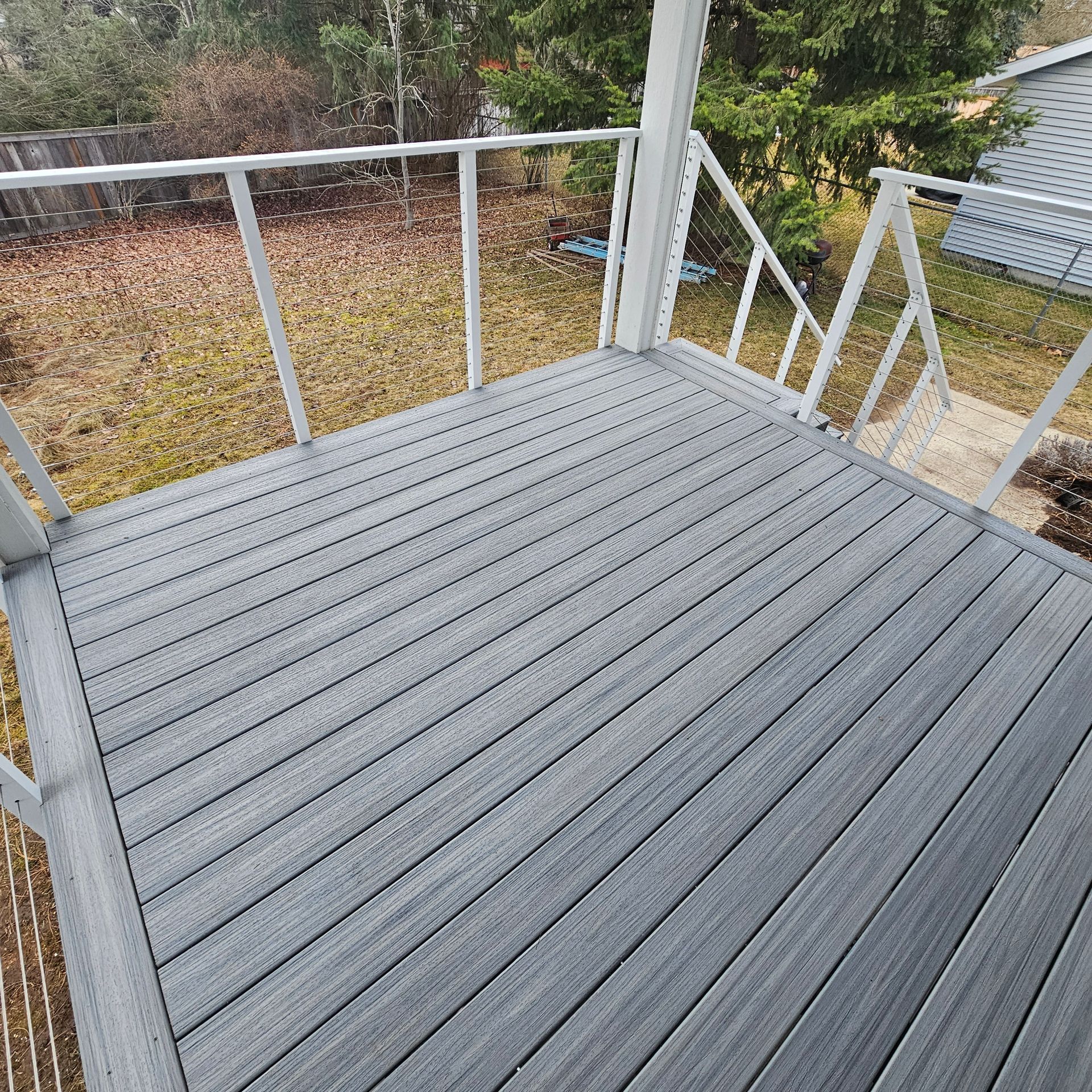 Gray composite deck with white railing in a backyard setting.
