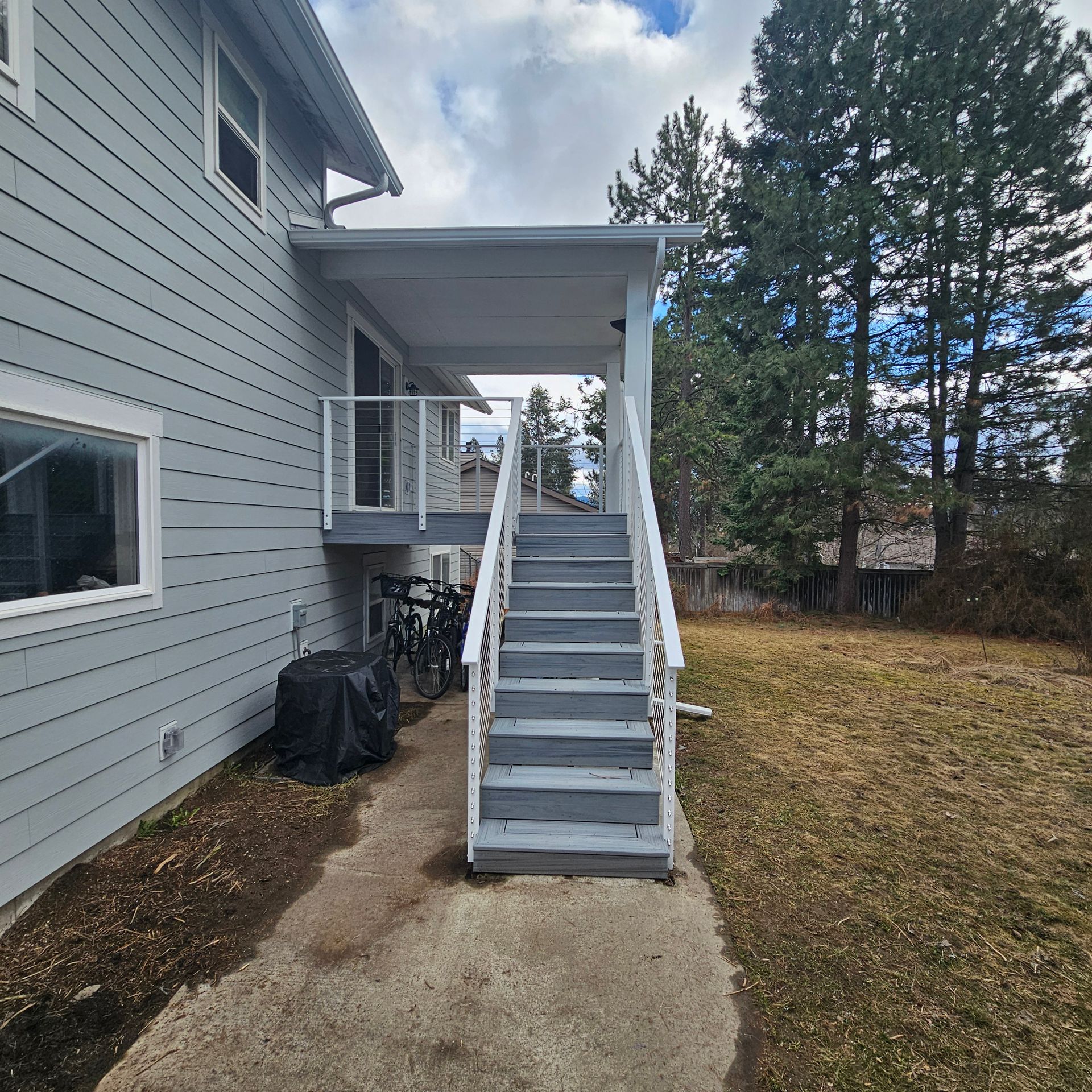 Gray house exterior with a covered porch and stairs leading down to a concrete path.