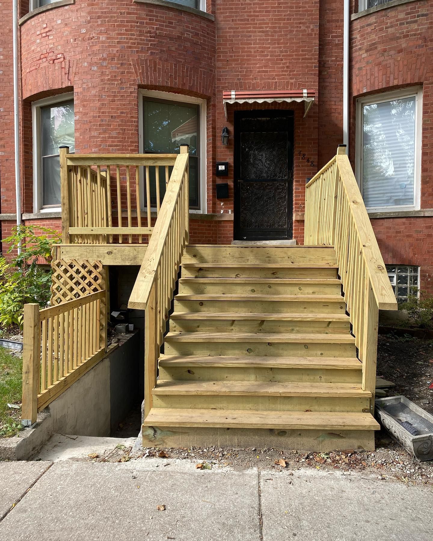 A wooden deck with stairs leading up to the front door of a brick building.