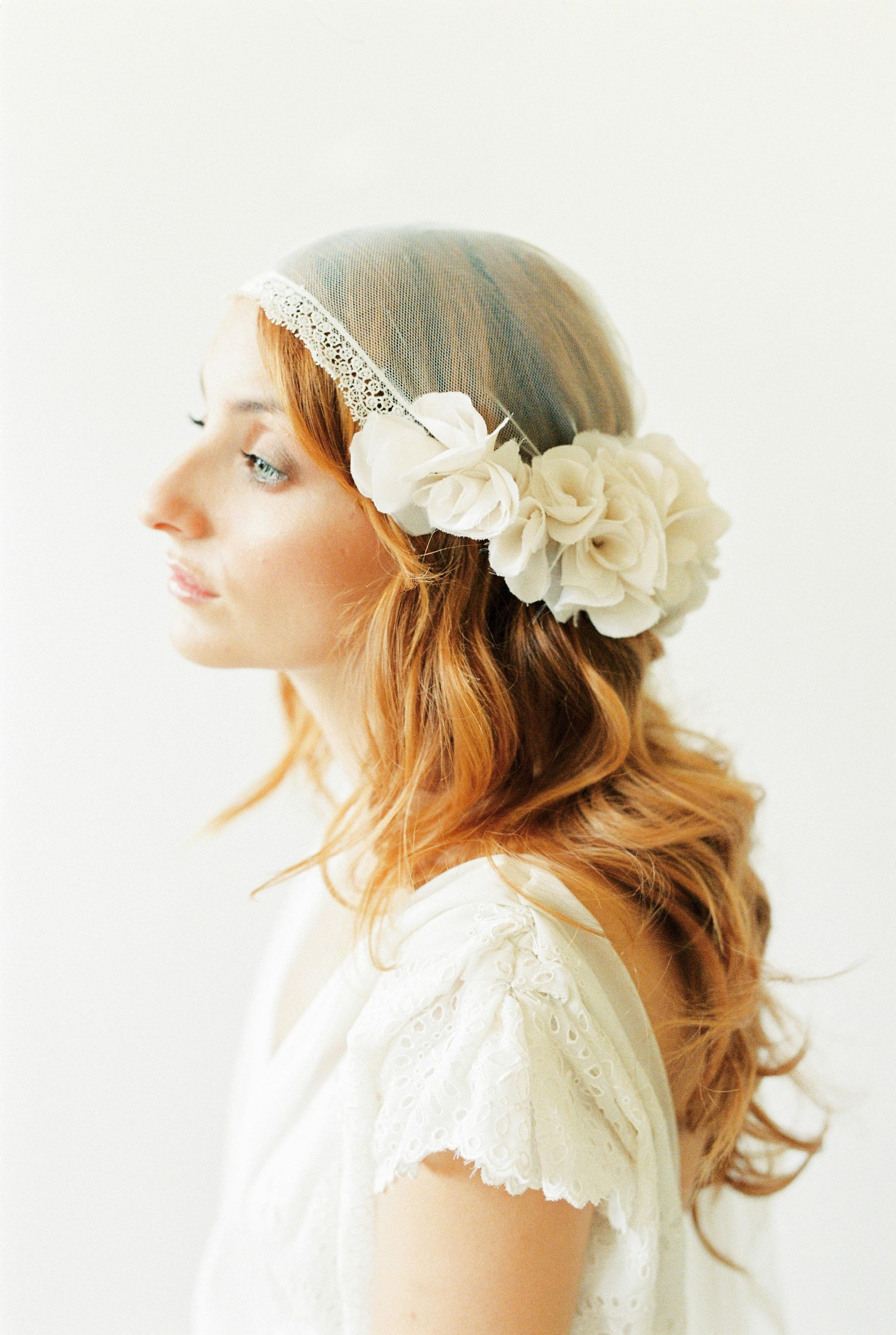 A woman in a white dress is wearing a headband with flowers in her hair.