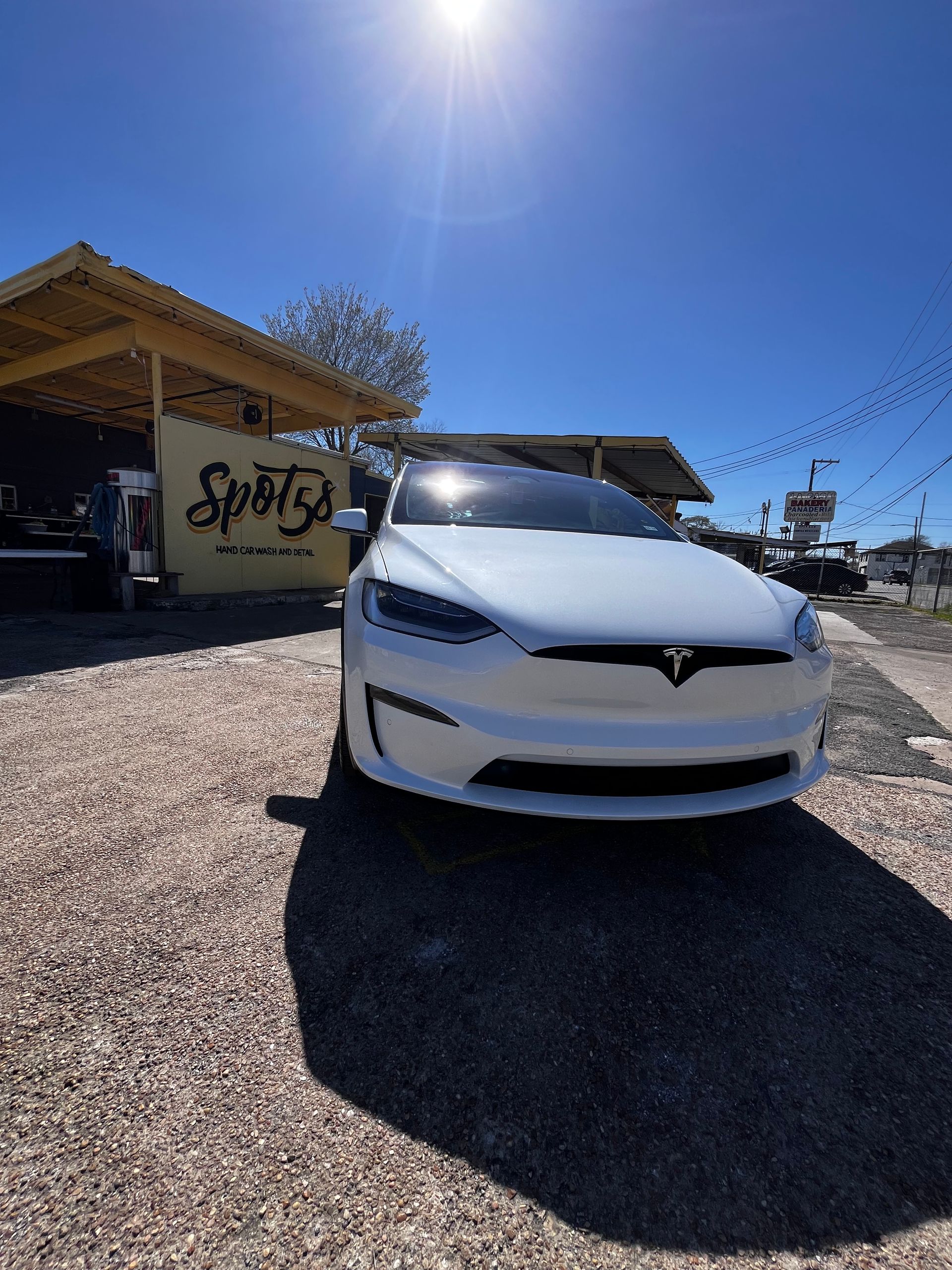 A white tesla model x is parked in front of Spot58 Car Wash and Detail Center in North Houston