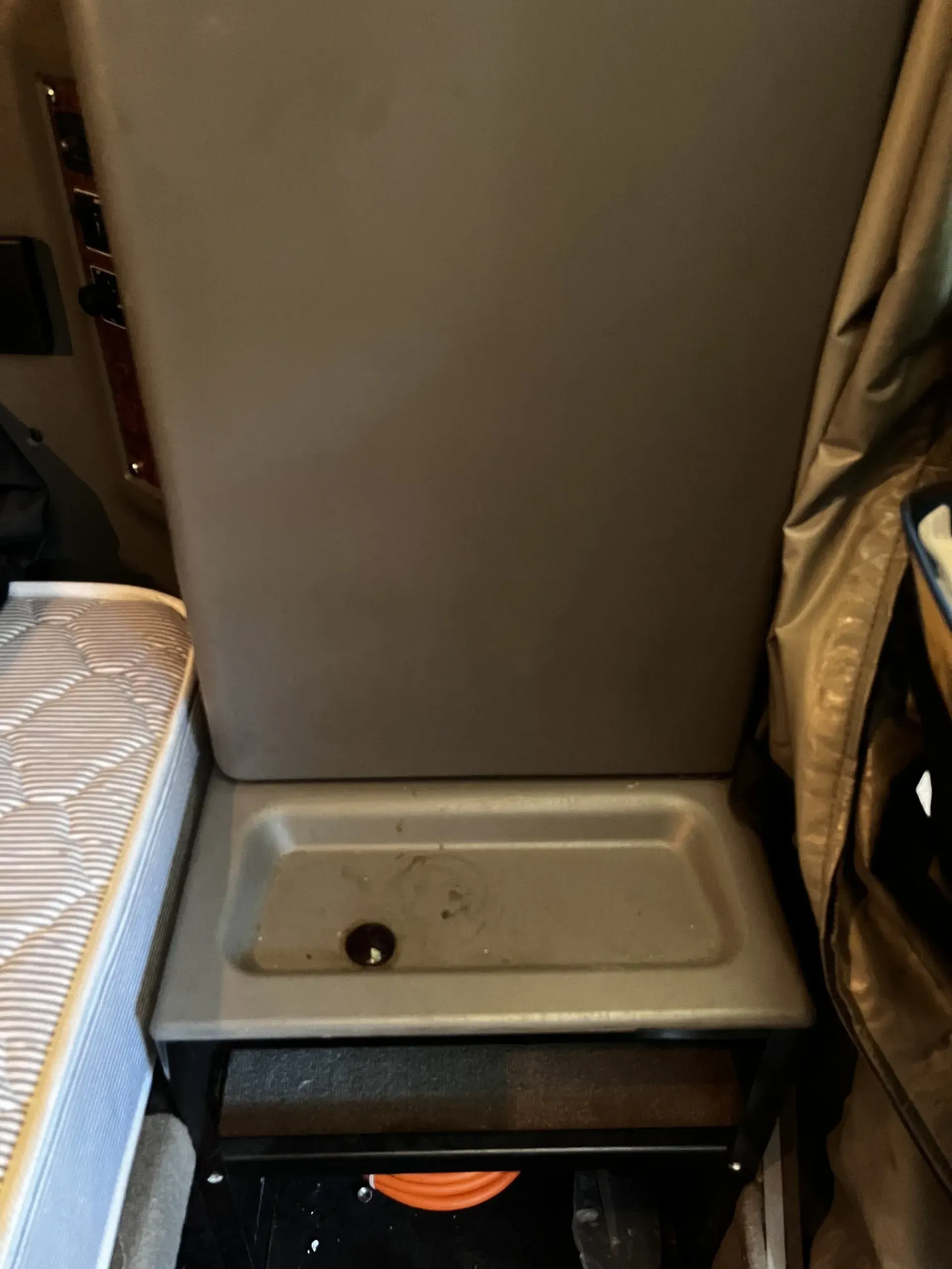 A mattress is sitting next to a chair with a sink underneath it.
