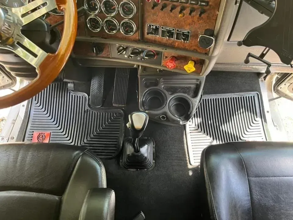 The interior of a semi truck with a wooden steering wheel.