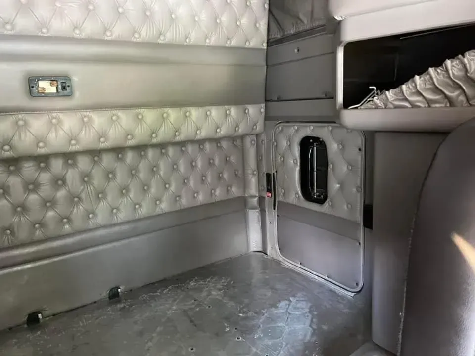 The inside of a semi truck with a bed and a window.
