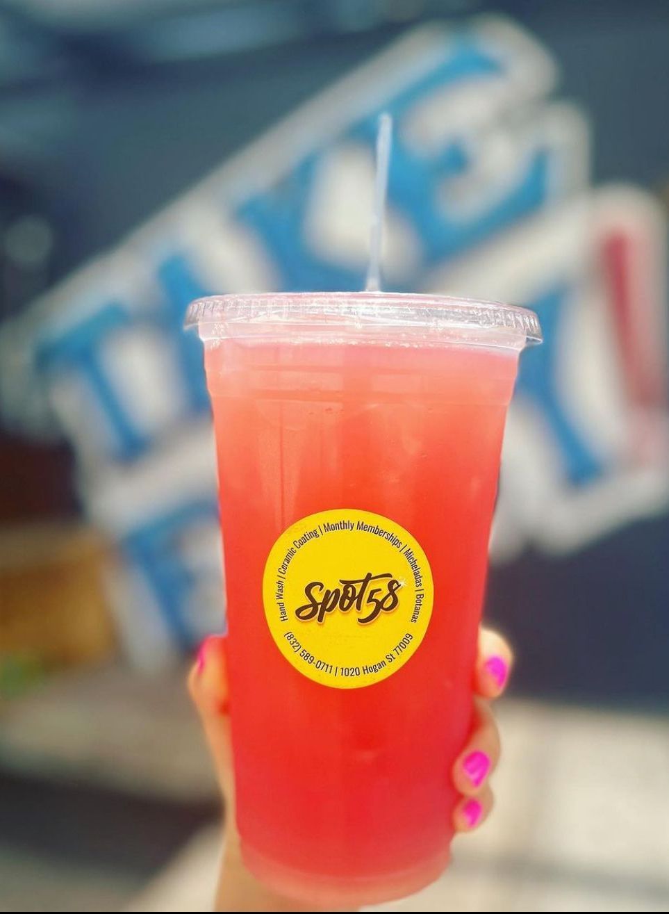 A person is holding a red drink with a yellow sticker that says spotty 's