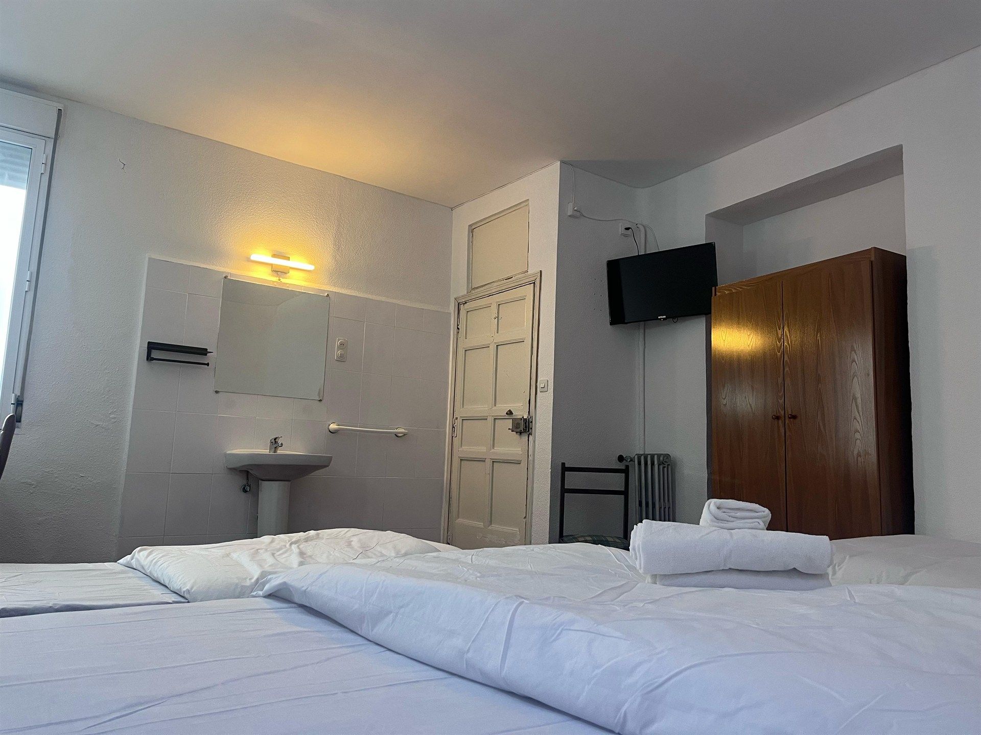 A hotel room with a bed , sink , and television.