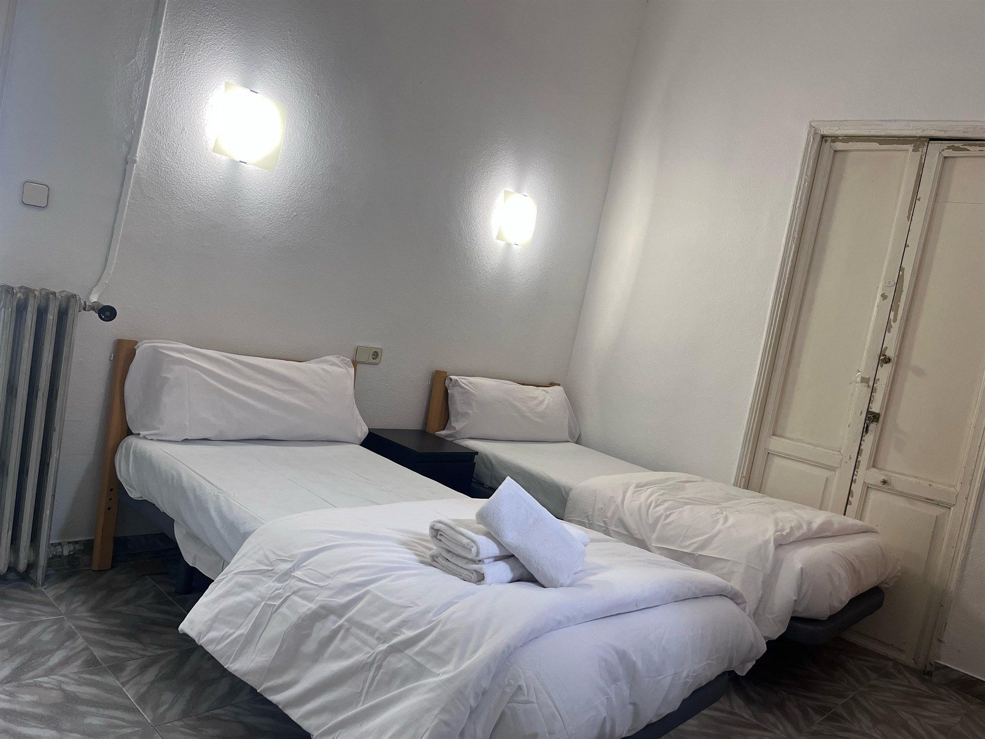 A bedroom with two beds and a radiator.