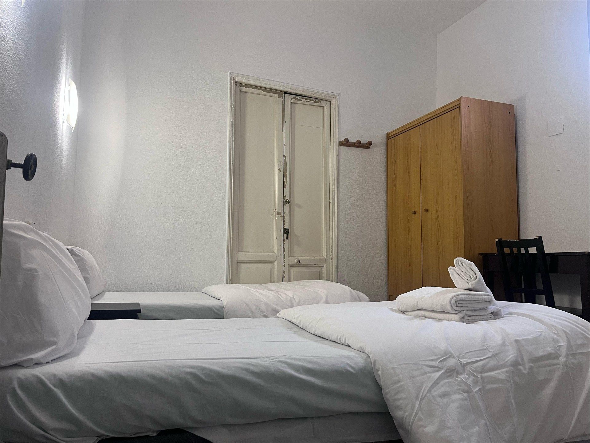 A hotel room with two beds , a desk and a wardrobe.