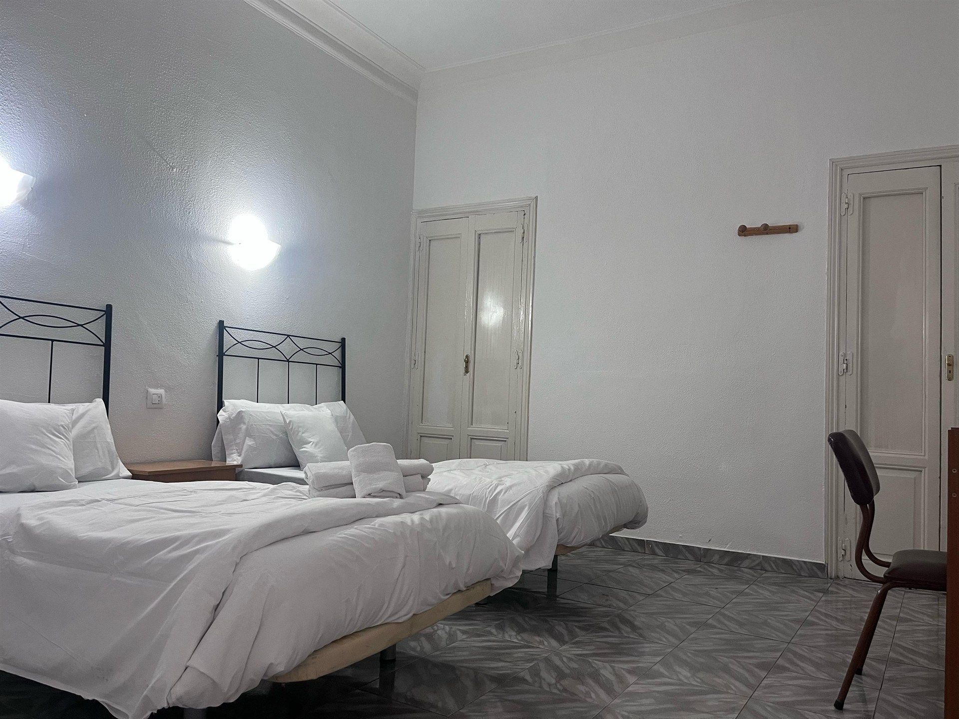 A hotel room with two beds , a desk and a chair.