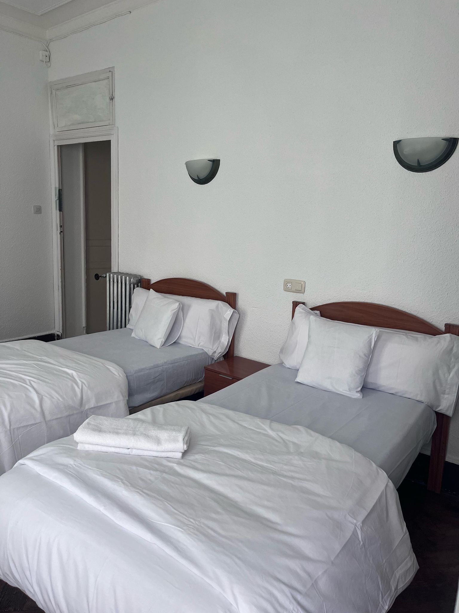 A hotel room with two beds and two nightstands.