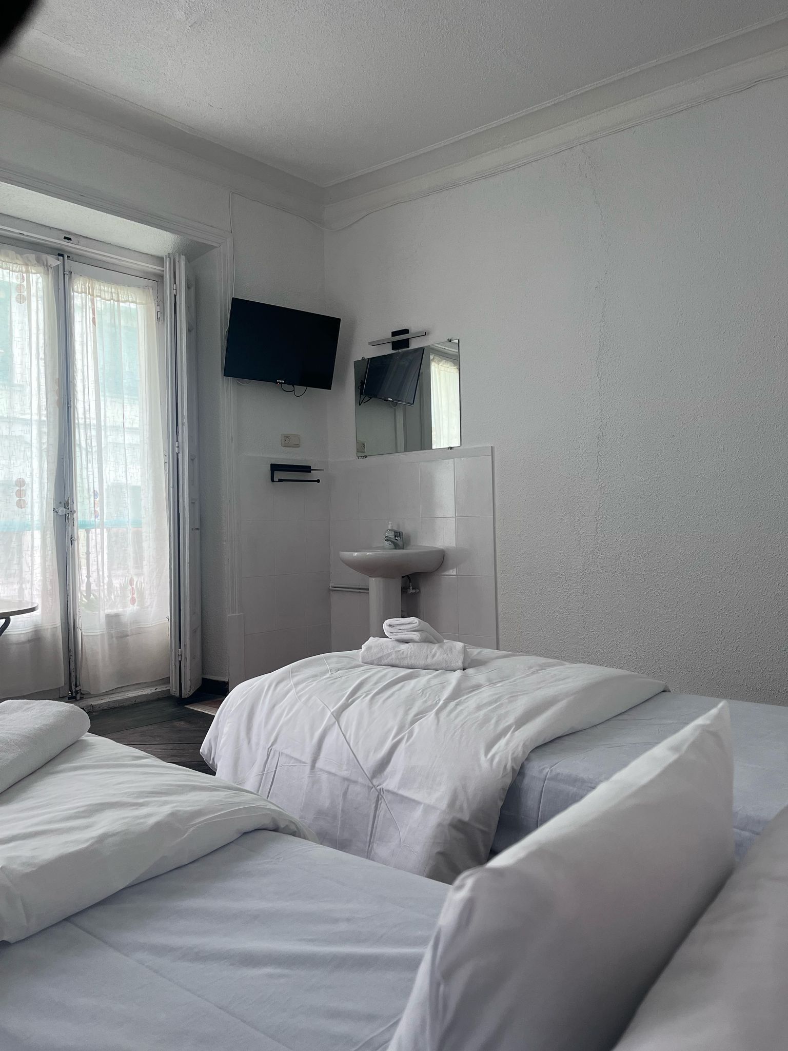 A hotel room with two beds , a sink and a television.