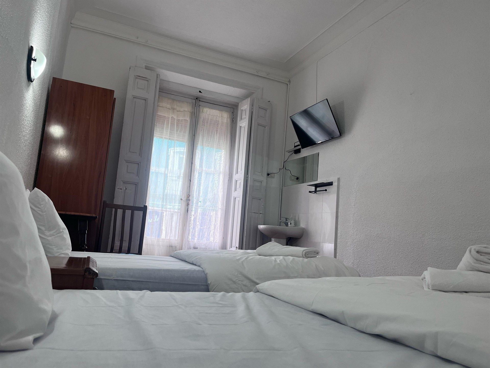 A hotel room with two beds , a sink and a television.