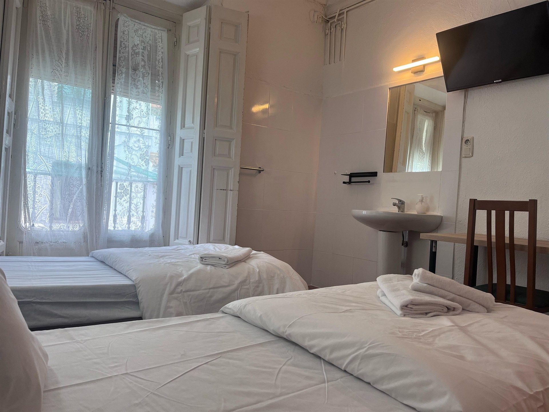 A hotel room with two beds , a sink and a television.