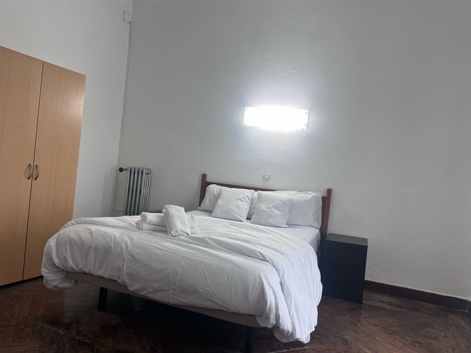 A bedroom with a bed , nightstand , and wardrobe.